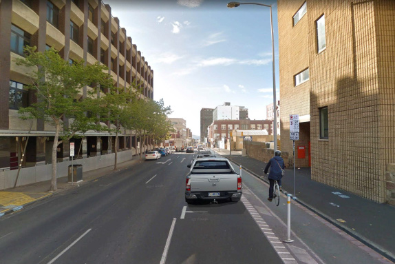 An artist's impression of a new bike lane along Campbell St in Hobart. There is a cyclist riding in the bike lane and cars parked on the street.