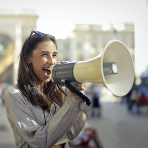 A woman talking through a loudspeaker on a street