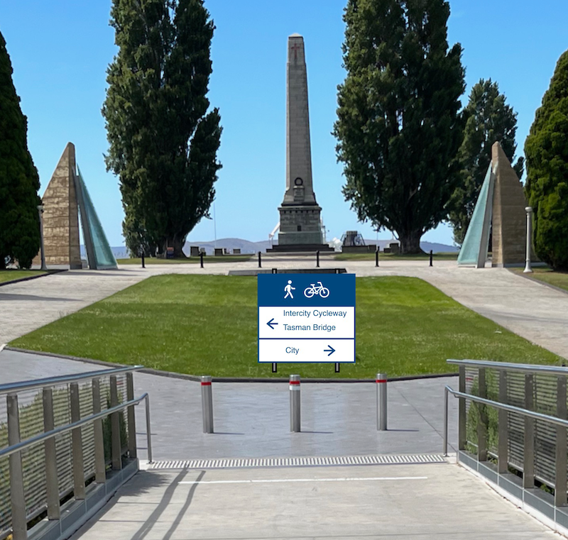 A photo taken coming off the eastern end of the Bridge of Remembrance. A wayfinding sign for pedestrians and cyclists has been added which shows Intercity Cycleway and Tasman Bridge to the left and City to the right.