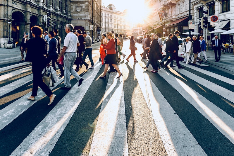 Lots of people walking across a pedestrian crossing at sunset