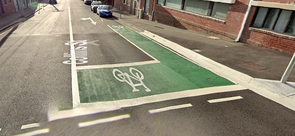 A photo of Collins Street near the intersection with Molle Street showing a few metres of green painted bike lane leading into a green painted bike box.