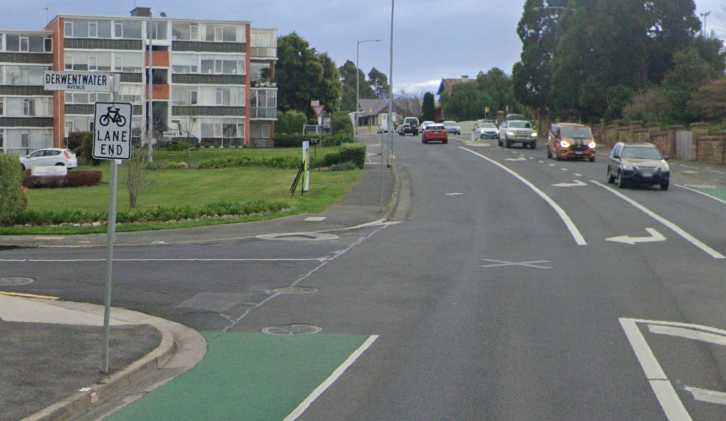 A green painted bike lane on Sandy Bay Road abruptly stops. There's a 'Bike Lane End' sign.