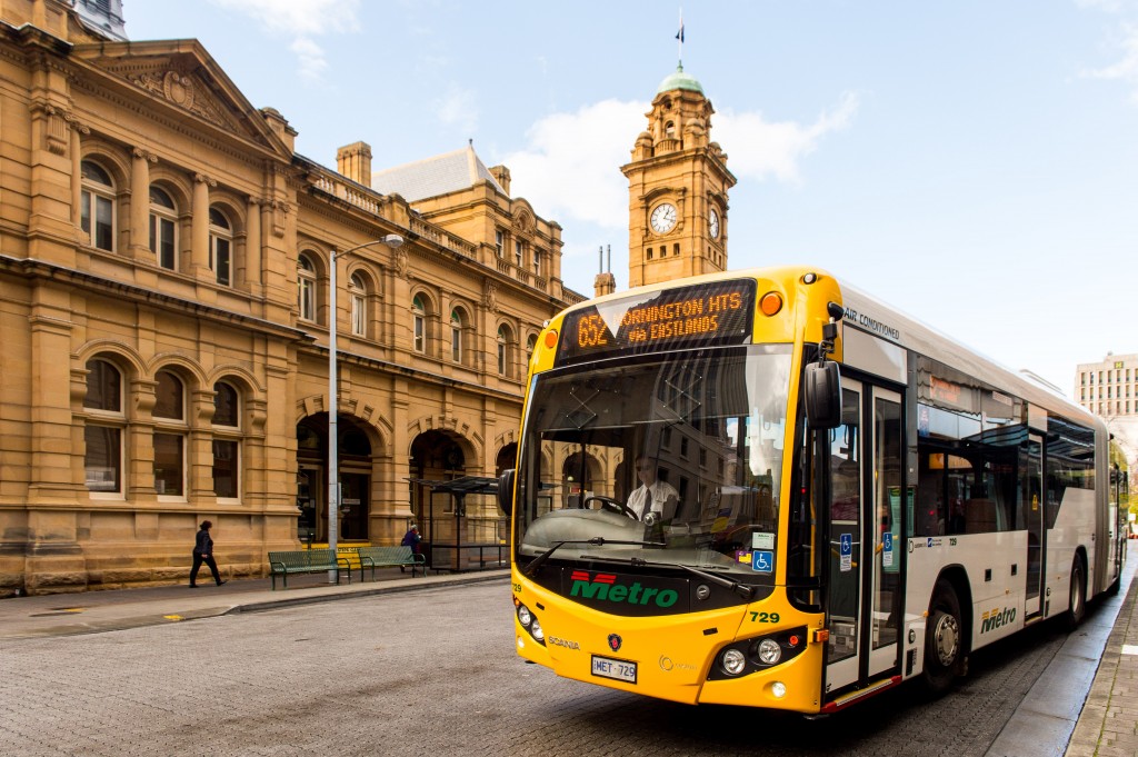 A Metro Tasmania bus leaving a bus stop in the Hobart Bus mall. The Hobart General Post Office is in the background.