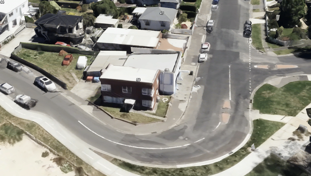 A photo showing a view looking down on the intersection of Queen Street with Victoria Esplanade near Bellerive Beach There are wide streets with pedestrian refuges, with minimal greenery. There are several parked cars.