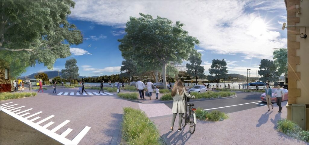 A photo showing the view approaching the Bellerive Pier from Cambridge Road. There's raised pedestrian crossings and lots of plants. There's a few parked cars and lots of people walking.