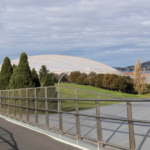 A photo looking east along the Bridge of Remembrance in Hobart. The cenotaph is in the left of the background and an artists impression of the planned Macquarie Point stadium is in the middle of the background.