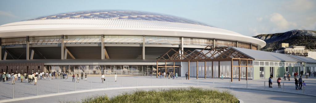 An artists impression showing a stadium with a domed roof. In the foreground is a concrete turning circle and plaza. There are lots of people in the plaza. A large wooden shed sits adjacent to the stadium and in to background are some city buildings and a snow capped mountain.