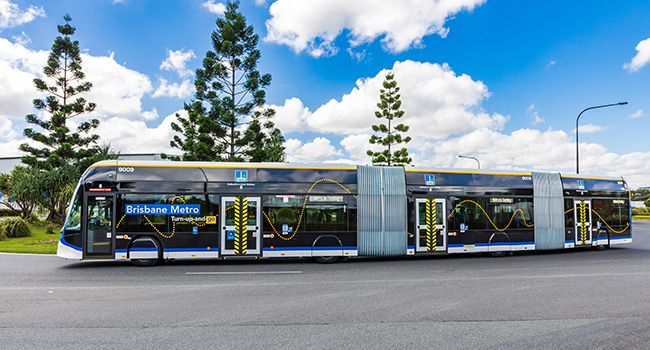 A long bus with two articulations driving on a road.