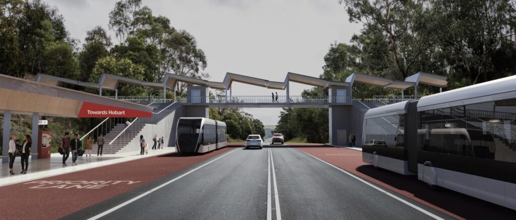 An artists impression of a modern looking bus rapid transit station. People are waiting on covered platforms. A red sign read "Towards Hobart". Two sleek silver articulated buses are driving in opposite directions on red lanes marked"Priority Lane". Cars drive in both directions on two general traffic lanes between the bus lanes. Stairs lead to a pedestrian overpass connecting the two platforms.