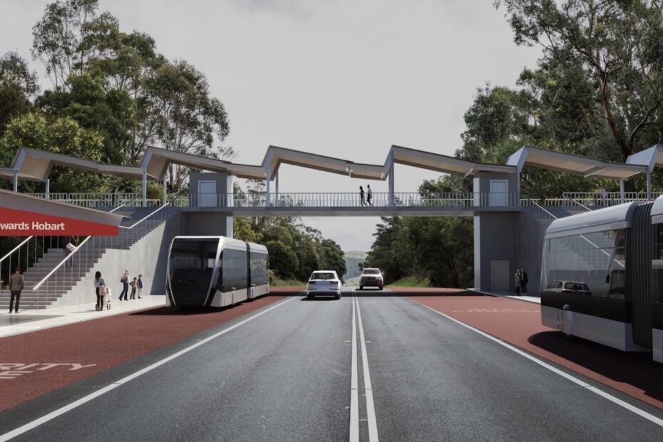 An artists impression of a modern looking bus rapid transit station. People are waiting on covered platforms. A red sign read "Towards Hobart". Two sleek silver articulated buses are driving in opposite directions on red lanes marked"Priority Lane". Cars drive in both directions on two general traffic lanes between the bus lanes. Stairs lead to a pedestrian overpass connecting the two platforms.