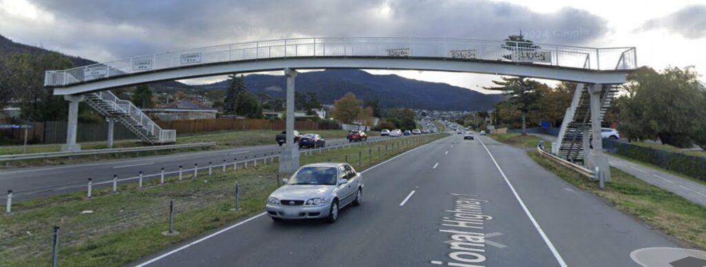 A Google Street View photo showing the old fashioned pedestrian overpass over the dual lane divided Brooker Highway at Montrose. The overpass has steep stairs at each end. Multiple cars are driving past in each direction.